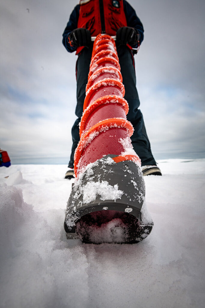 Person uses a Kovacs ice coring drill with T handle to take ice core sample