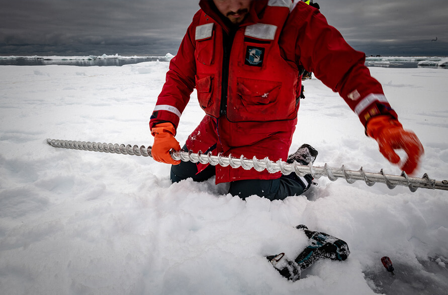 A researcher prepares to use a Kovacs ice auger mechanical drill to take an ice sample core